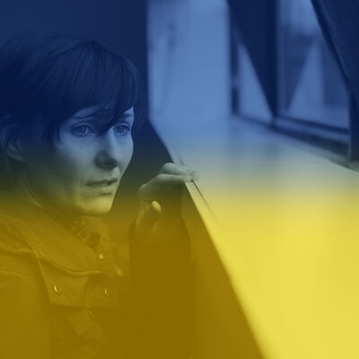 Eine Frau schaut durch ein Fenster und sieht traurig aus. Das Bild ist mit den Farben der Ukraine blau-gelb eingefrbt.