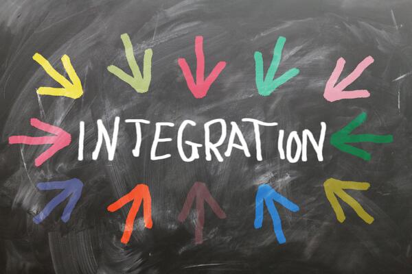 Auf einer Tafel steht das Wort Integration. Viele farbige Pfeile zeigen auf das Wort.