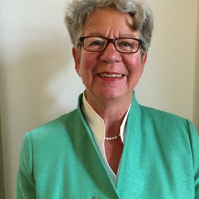 Eine Frau steht vor einem grauen Hintergrund. Sie trgt ein mintfarbenes Oberteil.