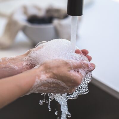 Ein Mensch wäscht sich seine Hände unter einem Wasserhahn.