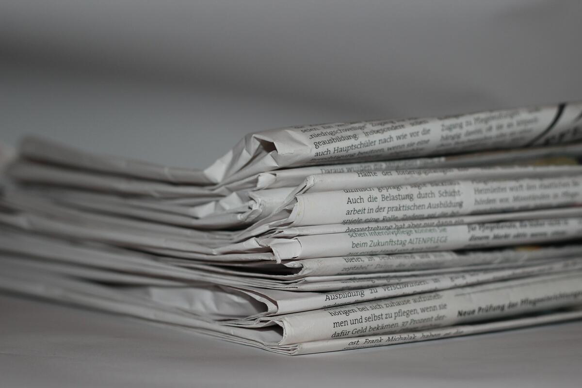 Mehrere Zeitungsseiten liegen  auf einem Stapel übereinander.