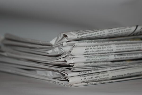 Mehrere Zeitungsseiten liegen auf einem Stapel übereinander.