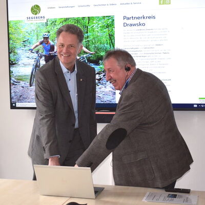 Die beiden Landrte der Partnerkreise drcken auf eine Taste auf einem Laptop, um die Onlineprsenzen der Partnerkreise freizuschalten.