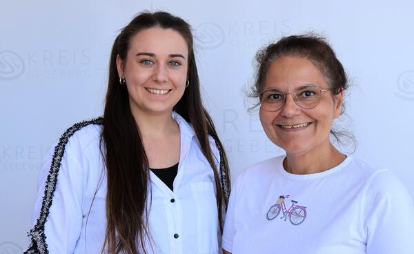 Fachdienstleiterin Frau Dr. Hakimpour-Zern (rechts) und Gesundheitsplanerin Juliane Kokot (links) lächeln. Beide tragen ein weißes Oberteil.