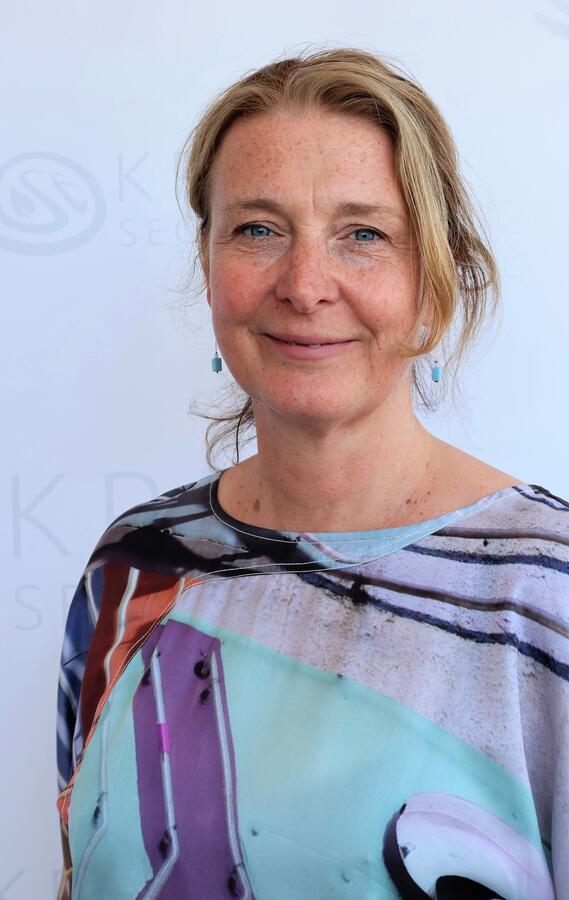 Ein Portrait der Sozialplanerin Denise Daude-Oster. Sie trägt eine bunt bedruckte Bluse ohne Kragen.