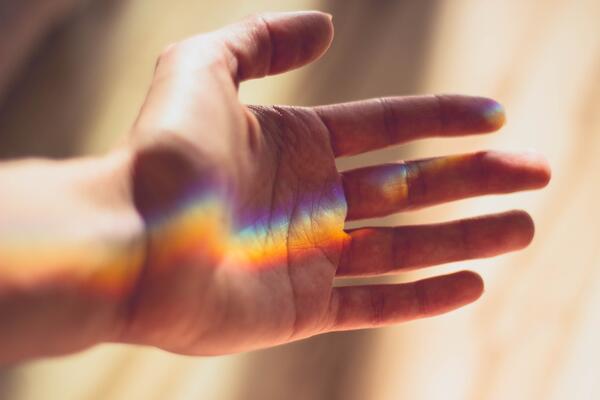 Ausgestreckte Hand mit Regenbogenschimmer auf der Handinnenfl&auml;che.