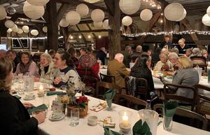 Viele Menschen sitzen an mehreren Tafeln in einem Restaurant und unterhalten sich.