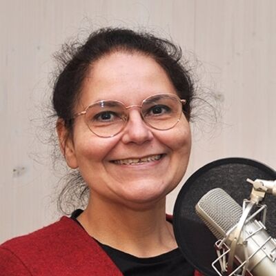 Eine Frau steht vor einem Mikrofon und lächelt.