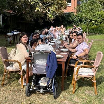 Viele Menschen sitzen an einer langen gedeckten Tafel.