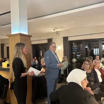Kreispräsident Jörg Buthmann spricht stehend vor einem sitzenden Publikum.