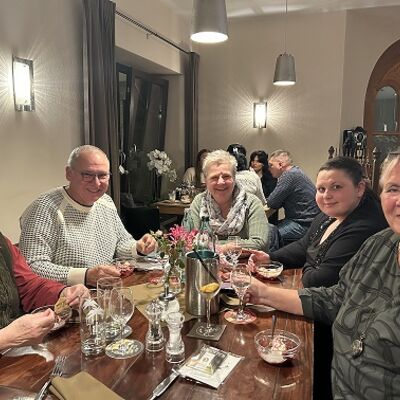 Mehrere Menschen sitzen an einem gedeckten Tisch.