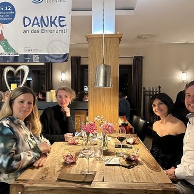 Mehrere Menschen sitzen an einem gedeckten Tisch.