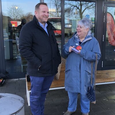 Ein Mann und eine Frau unterhalten sich vor einer Glasfassade.