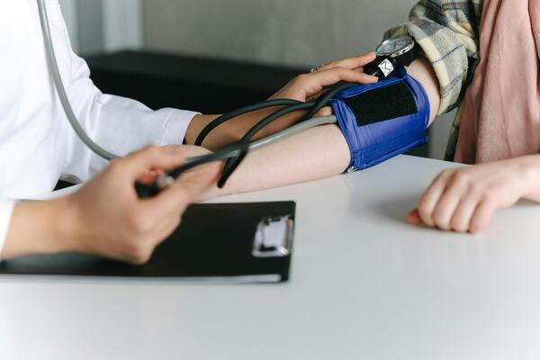 Eine Person aus dem medizinischen Bereich misst den Blutdruck einer Patientin.
