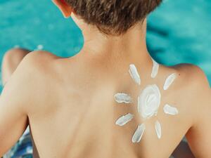 Ein Kind am Pool hat Sonnencreme auf der rechten Schulter.