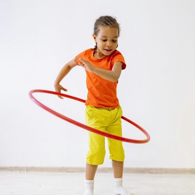 Ein kleines Mädchen lässt eine Ring um die Hüften kreisen.