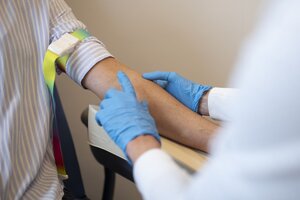 Eine medizinische Fachkraft bereitet eine Patientin f&uuml;r eine Blutabnahme vor. Der Arm ist abgebunden.