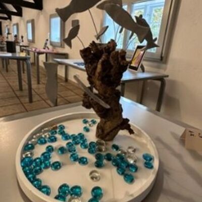 Ein Kunstwerk mit Fischen und Glassteinen steht auf einem Tisch.