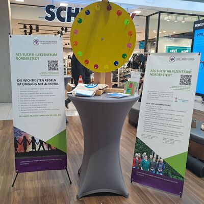 Ein Stand steht in einem Einkaufszentrum. Es sind Plakate mit Informationen aufgestellt.