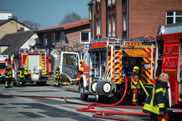 Mehrere Feuerwehrautos und ein Krankenwagen sind bei einem Einsatz in einem Wohngebiet.