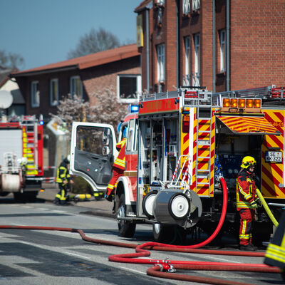 Mehrere Feuerwehrautos und ein Krankenwagen sind bei einem Einsatz in einem Wohngebiet.