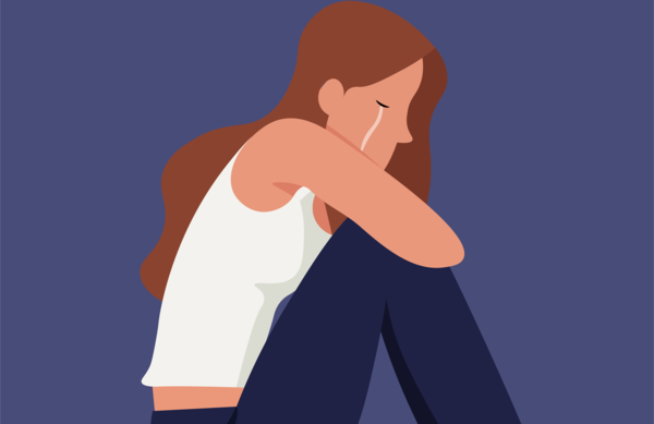 Ein Mdchen oder eine junge Frau weint im Sitzen. Die Knie sind an den Krper schtzend herangezogen.